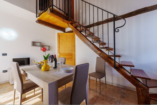 A dining area with a wooden table, chairs, and a staircase with a wooden railing.