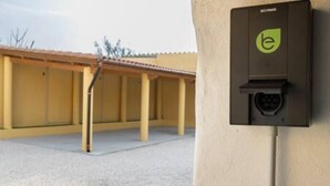 Une boîte électrique noire, ornée d’un logo, est fixée au mur.