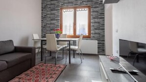 Un salon moderne avec un mur d’accent en pierre, un coin repas avec une table et des chaises, et un canapé.
