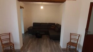 A living room with a dark-colored sofa, two wooden chairs, and a coffee table. - Casa Aida al Centro di Nurachi (Nurachi)