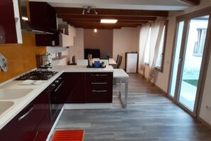 Une cuisine moderne avec des meubles de couleur sombre, un plan de travail blanc et une cuisinière à gaz.