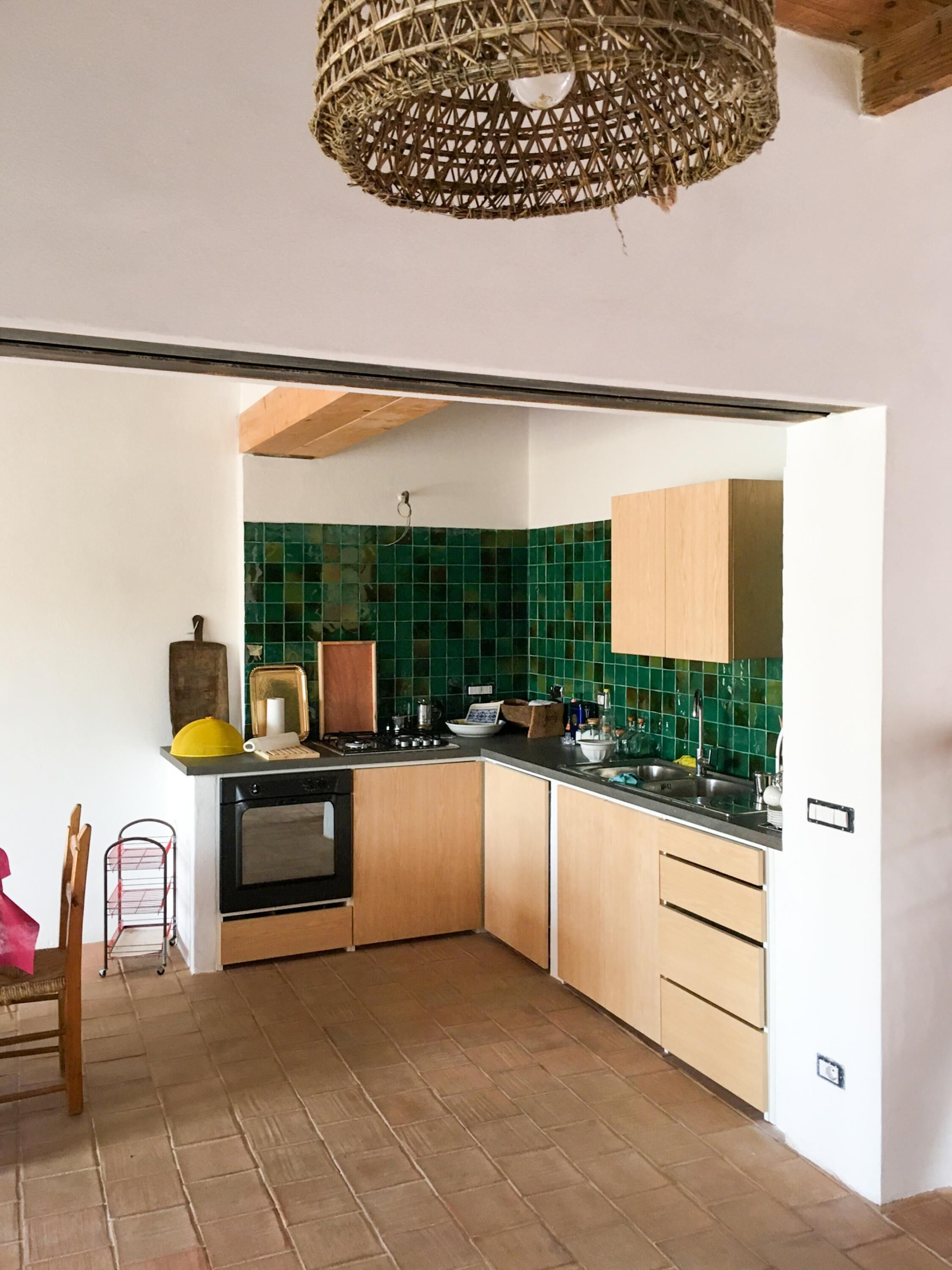 A kitchen with wooden cabinets, a black stove, and green tiled backsplash.