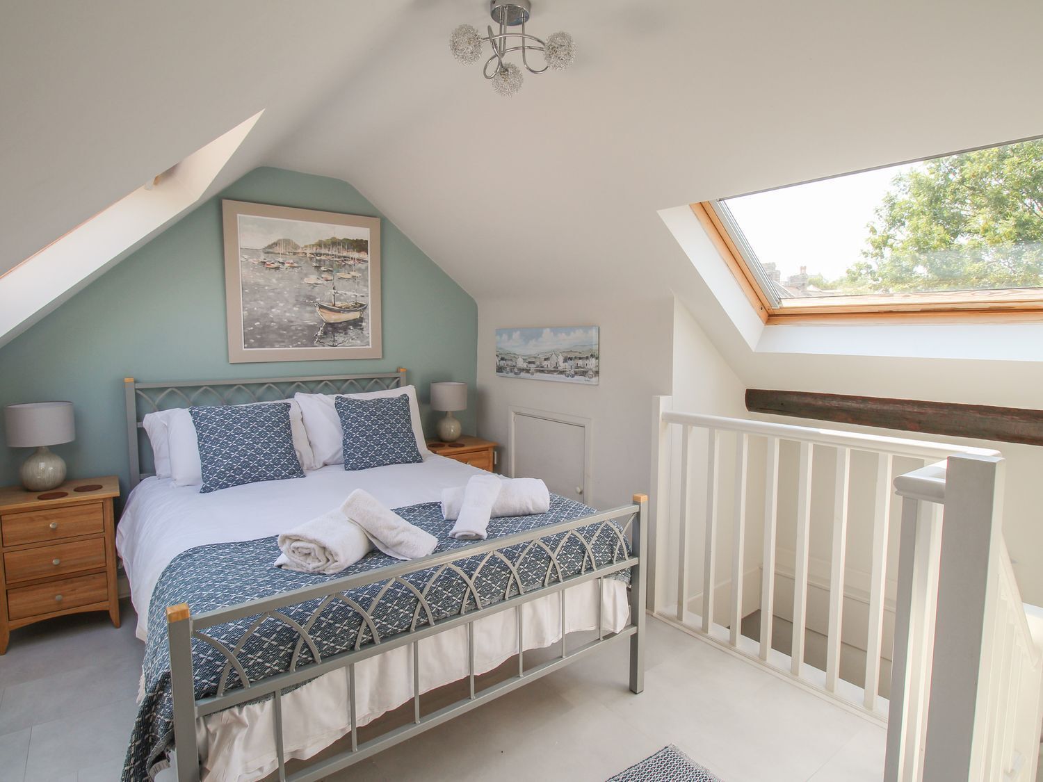 Une chambre à coucher comprenant un lit, des tables de chevet, un luminaire au plafond, une fenêtre et une vue sur l’extérieur.