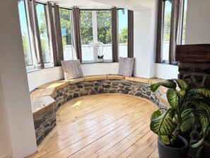 A room with a stone bench, wooden flooring, and large windows with curtains. - Pembrokeshire | Beach, Pool, Hot Tub | Large Group Accomodation | Sleeps 24 (Pembroke)