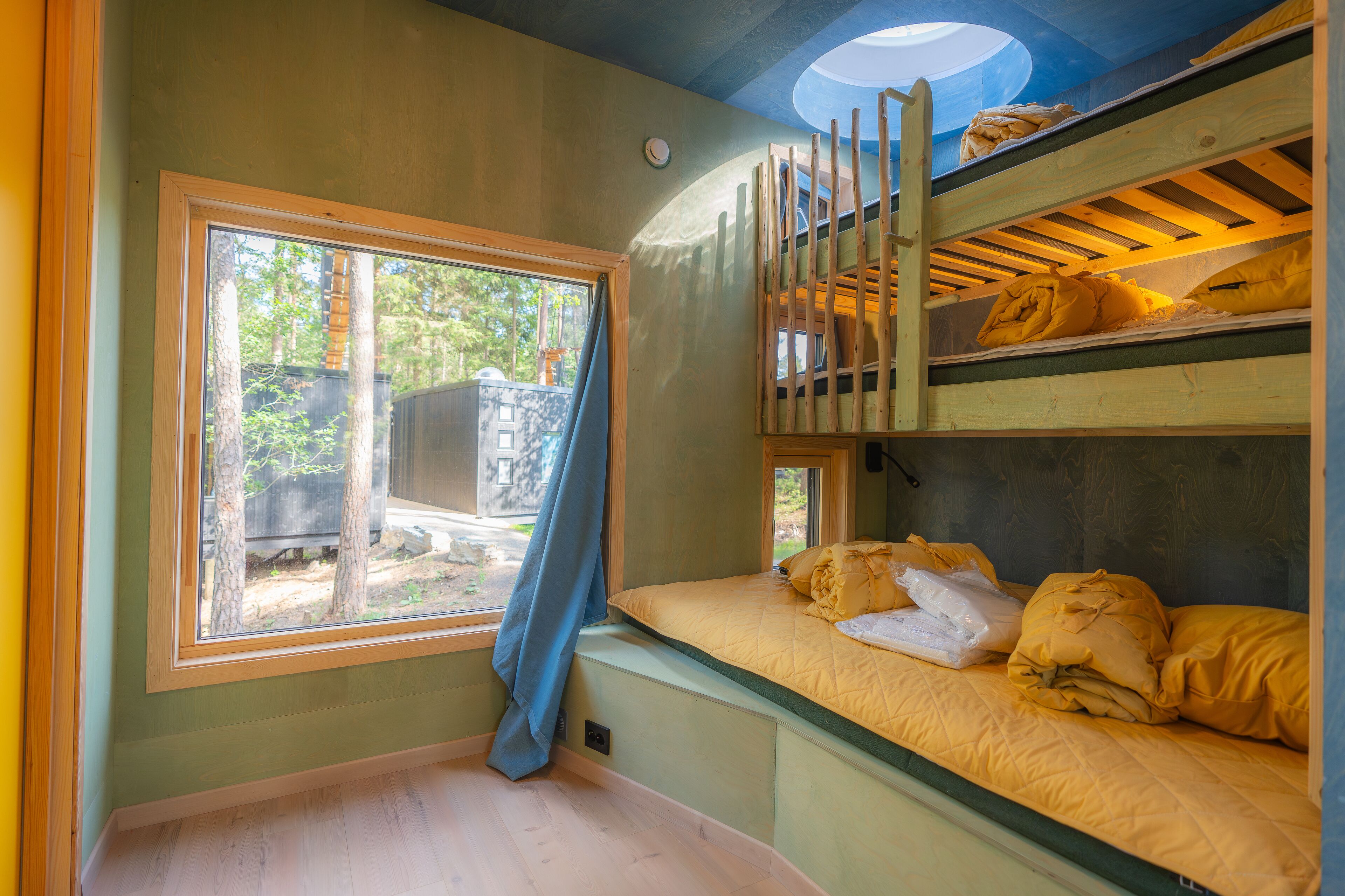 A bunk bed room with a window overlooking a yard.