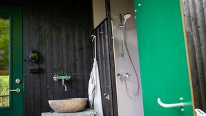 A rustic bathroom with a stone sink, a wooden door, and a green wall. - Juliusskogen  (Kristiansand)