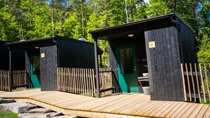 A wooden deck leading to a cabin with a green door, surrounded by a wooden fence and trees. - Juliusskogen  (Kristiansand)