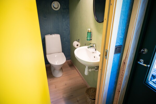 A compact bathroom with a toilet, sink, and a mirror. - Juliusskogen (Kristiansand)
