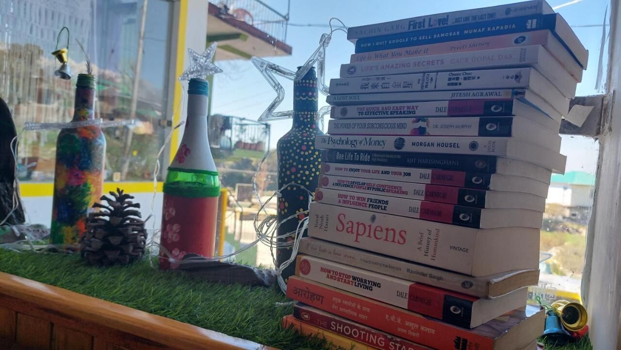 Una pila de libros en un alféizar con vistas al exterior.