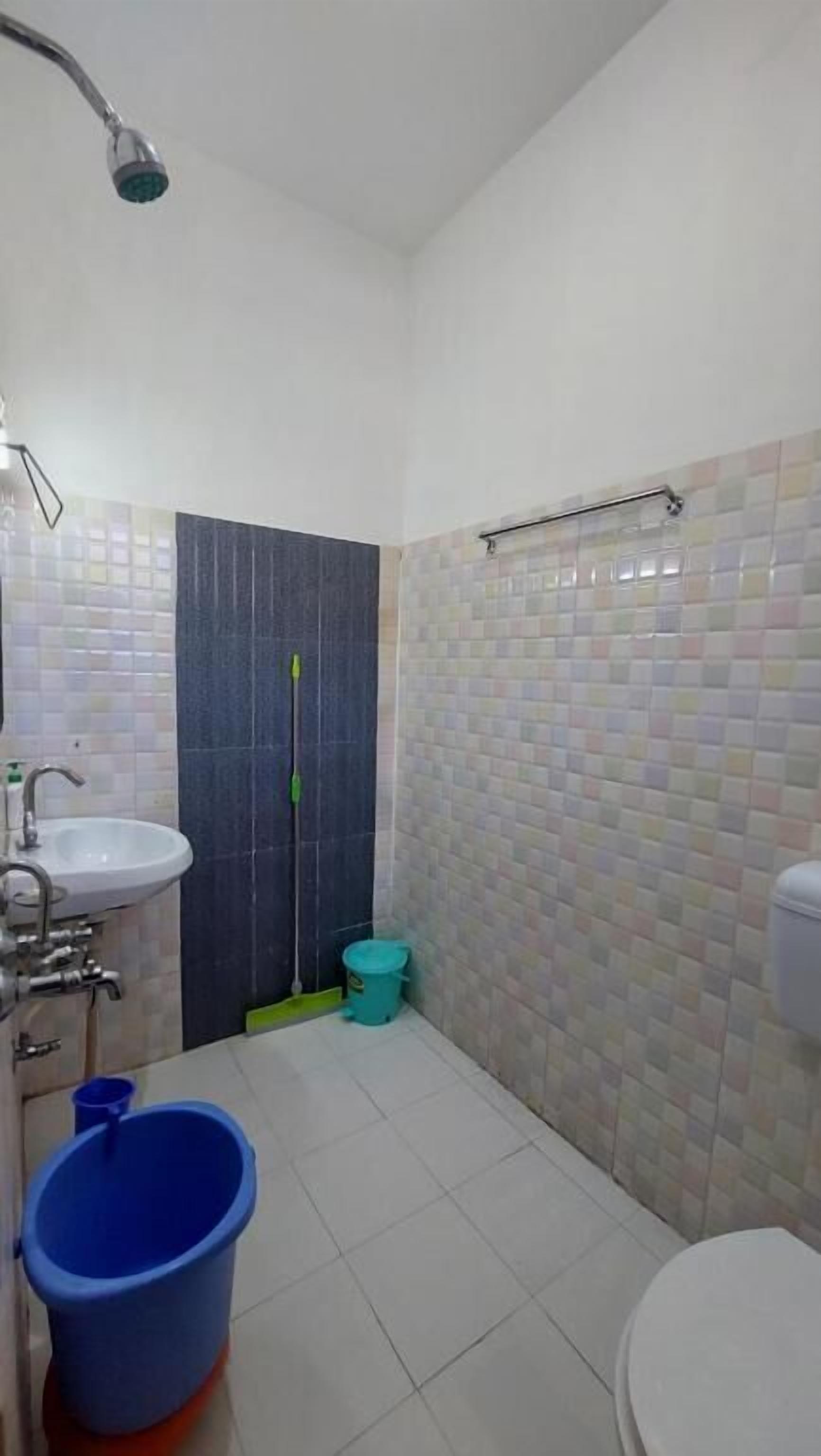 A bathroom with a sink, toilet, shower, and a mop.