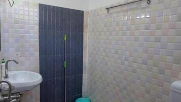 A bathroom with a sink, toilet, shower, and a mop.