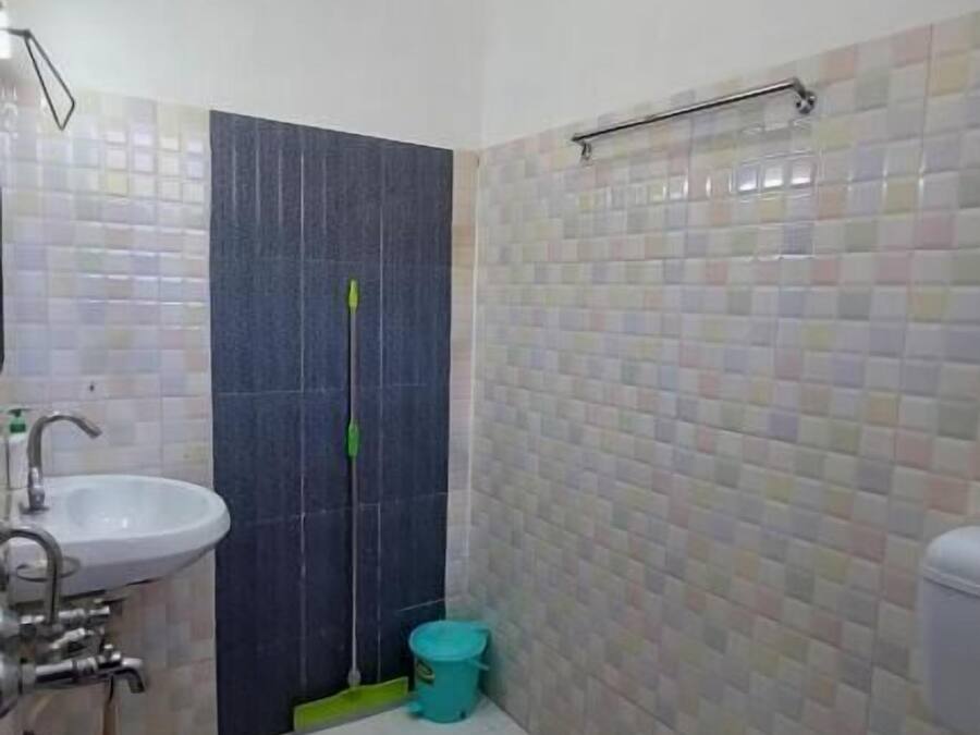 A bathroom with a sink, toilet, shower, and a mop.