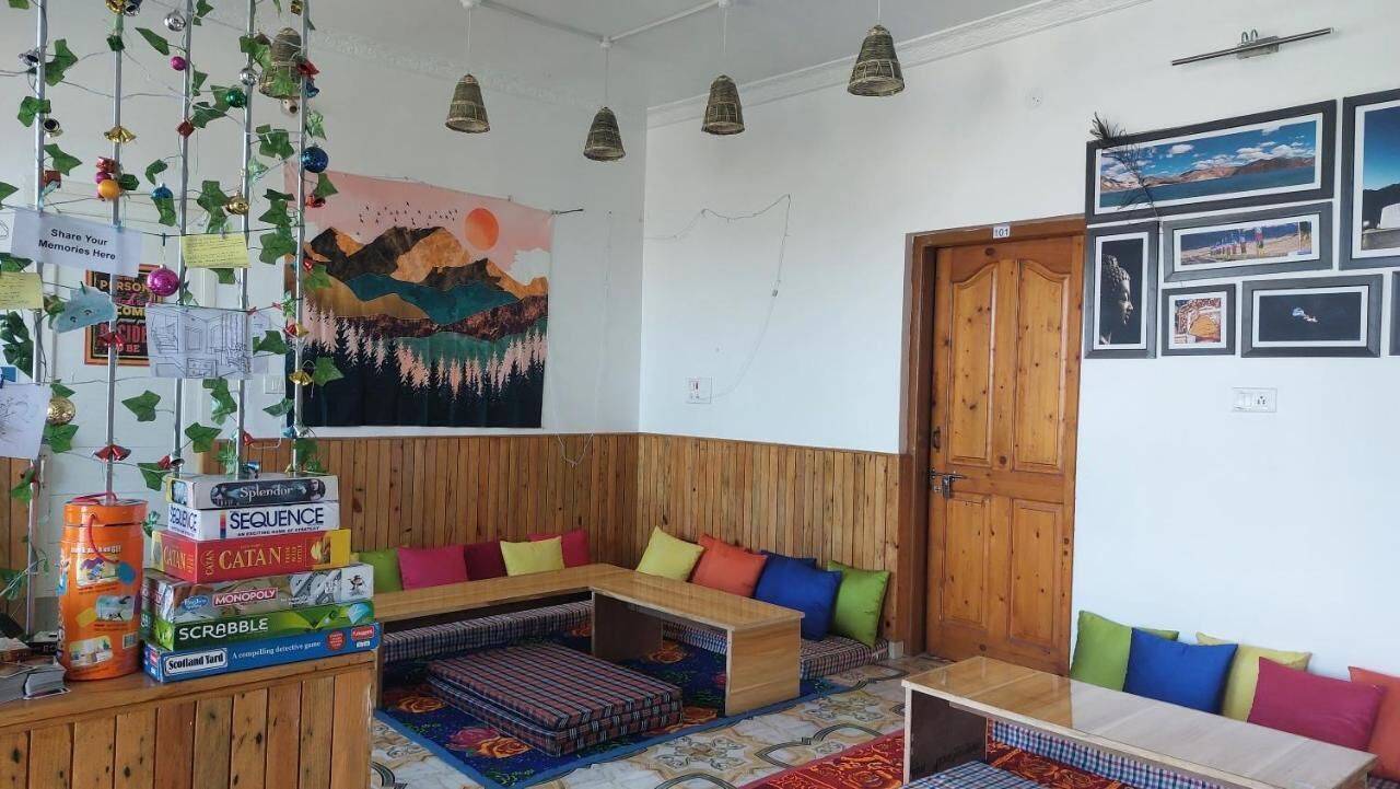 A cozy room with a wooden bench, colorful cushions, and a wall decorated with framed pictures and a mural.