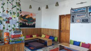 A cozy room with a wooden bench, colorful cushions, and a wall decorated with framed pictures and a mural.