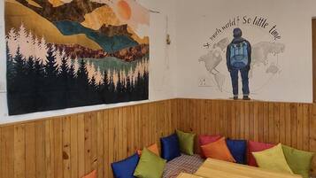 Una habitación acogedora con un gran mural de un paisaje montañoso y una persona con una mochila.