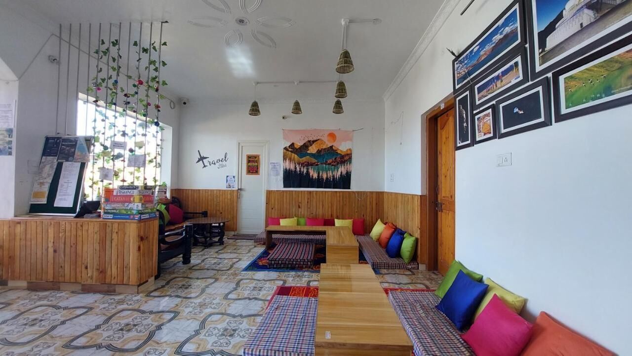 A hotel lobby with wooden furniture, a reception desk, and a wall with framed pictures.