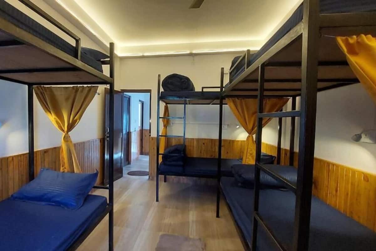 Een slaapkamer met stapelbed, houten wanden en een plafondventilator.