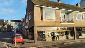 A building with a shop on the ground floor and a residential unit above. - Bay View Esplanade Apartment Overlooking Harbour (Oban)