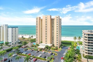 Um hotel moderno com vista para a praia, estacionamento e área de piscina.