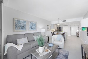 A modern living room with a grey sofa, a coffee table with a plant, and artwork on the wall.
