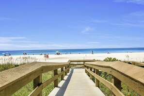 A wooden boardwalk leading to a beach with clear skies.
