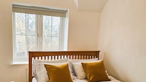 Una camera da letto con un letto di legno, una finestra vista, un comodino e un tavolino di fianco al letto.