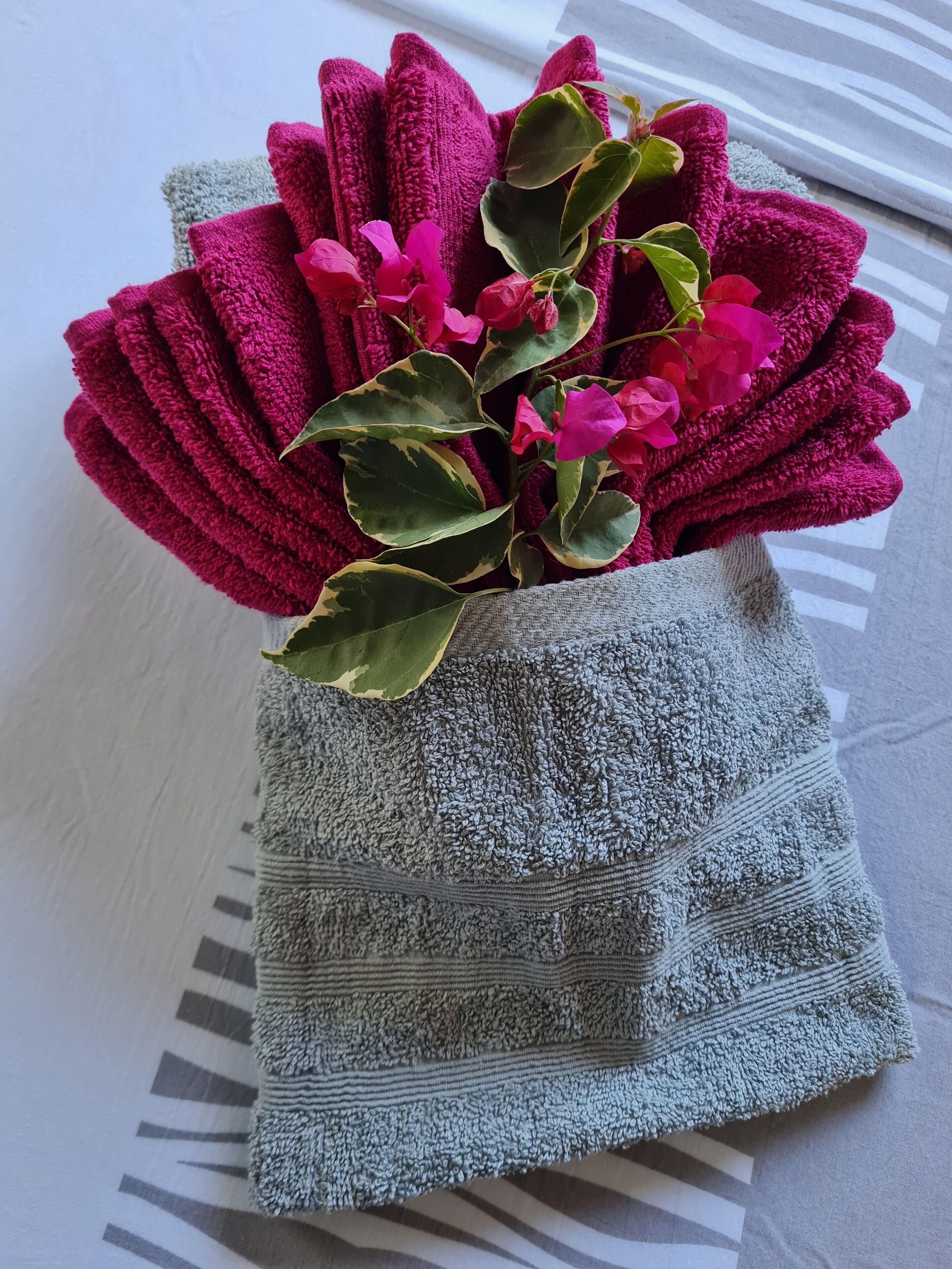 Une serviette grise ornée d’un bouquet de fleurs roses et de feuilles vertes.