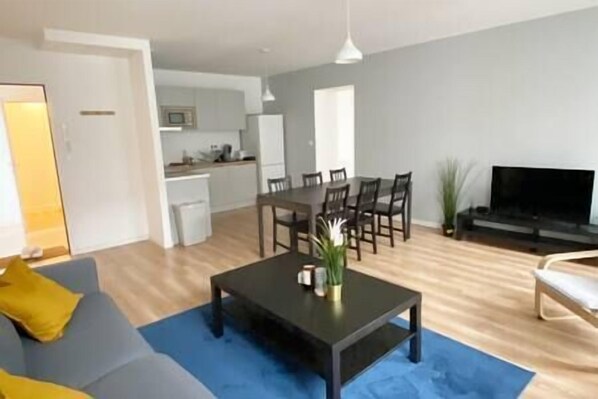Uma sala de estar moderna com um sofá, uma mesa de centro e uma área de jantar com cadeiras e uma mesa.