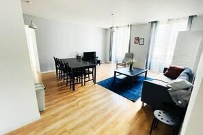 Uma sala de estar moderna com área de jantar, um sofá e uma mesa de centro.