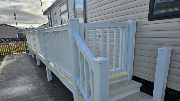 A white wooden deck with a staircase leading to a house with beige siding. - 208 Unity Beach 6 Berth enc Garden no Pets (Burnham-on-Sea)