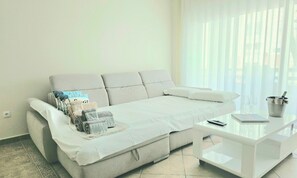 Una sala moderna con un sofá, una mesa de centro y un ventanal con persianas.