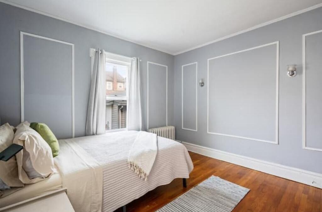Une chambre à coucher avec un lit, un radiateur et une fenêtre avec des rideaux.