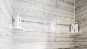 Un baño moderno con una bañera grande, paneles de pared de madera y dos dispensadores de jabón en estantes flotantes.
