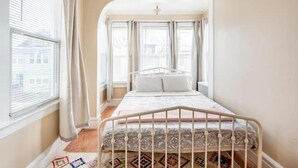 Ein Schlafzimmer mit Bett, Vorhängen und einem Fenster.