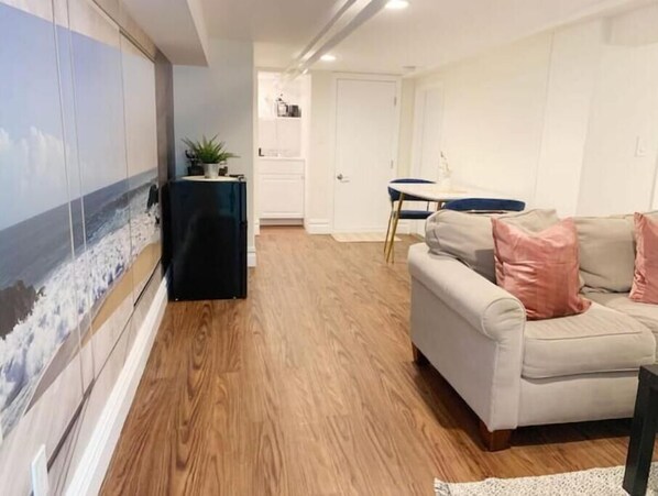 A living room with a beige sofa, a small table, and a plant.