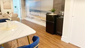 Una cocina moderna con encimera de mármol, un refrigerador negro y vistas a la playa a través de un amplio ventanal.