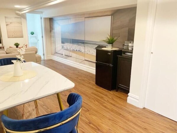 Una cocina moderna con encimera de mármol, un refrigerador negro y vistas a la playa a través de un amplio ventanal.