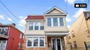 A two-story house with a front porch and a staircase leading to the entrance. - 2-BDR Oasis Near Beth Isreal Hosp 10 mins to EWR (Newark)