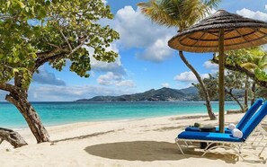 A beach with a clear view of the ocean, a lounge chair, and a thatched umbrella. - Park View Apartments Grenada (St. George's)