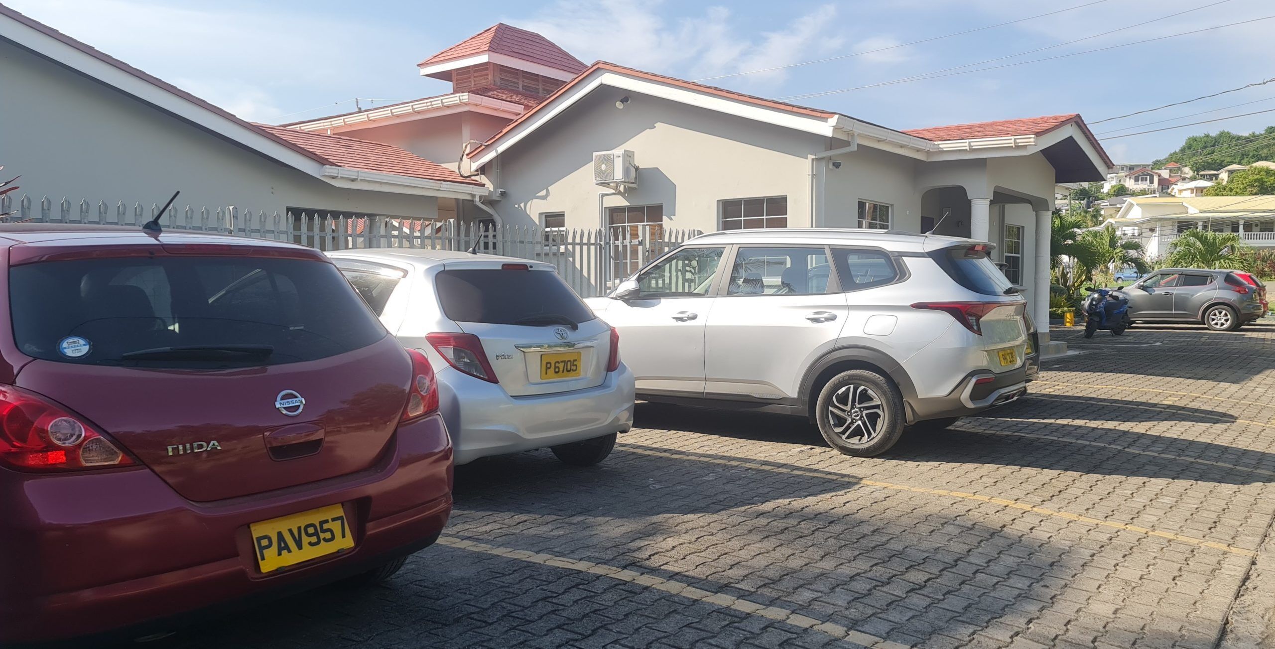 A parking area with several cars, including a red Nissan and a white SUV.