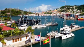 Un puerto deportivo con varias embarcaciones amarradas, una bandera y un edificio de techo rojo.