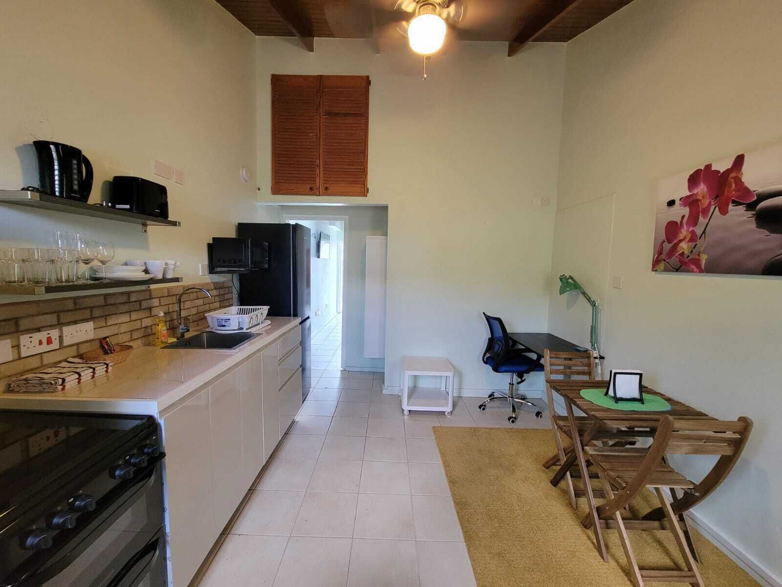 A compact kitchen with a stove, oven, and coffee maker. There is a small dining area with a table and chairs.