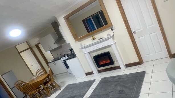 A living room with a fireplace, a dining area with wooden chairs, and a kitchen in the background. - Beautiful 3-bed Bungalow in Bawtry Doncaster (Doncaster)