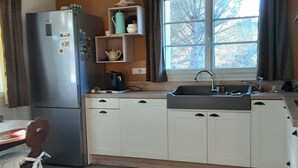 Una cocina compacta con refrigerador, cafetera y lavamanos.
