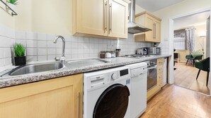 A modern kitchen with wooden cabinets, a built-in dishwasher, and a stainless steel sink. - 1 Bed Flat - Sleeps 5 - Pets - Parking - Wifi (London)