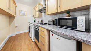 A kitchen with wooden cabinets, a built-in microwave, a stove, and a dishwasher. - 1 Bed Flat - Sleeps 5 - Pets - Parking - Wifi (London)
