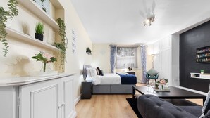 A modern bedroom with a bed, bedside table, lamp, and a small desk with a chair. - 1 Bed Flat - Sleeps 5 - Pets - Parking - Wifi (London)