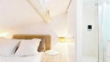 Een moderne slaapkamer met een groot bed, bedlampen en een klein rond tafeltje.