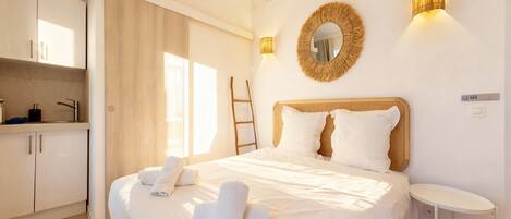 A hotel room with a bed, a bedside table, a wardrobe, and a bathroom.