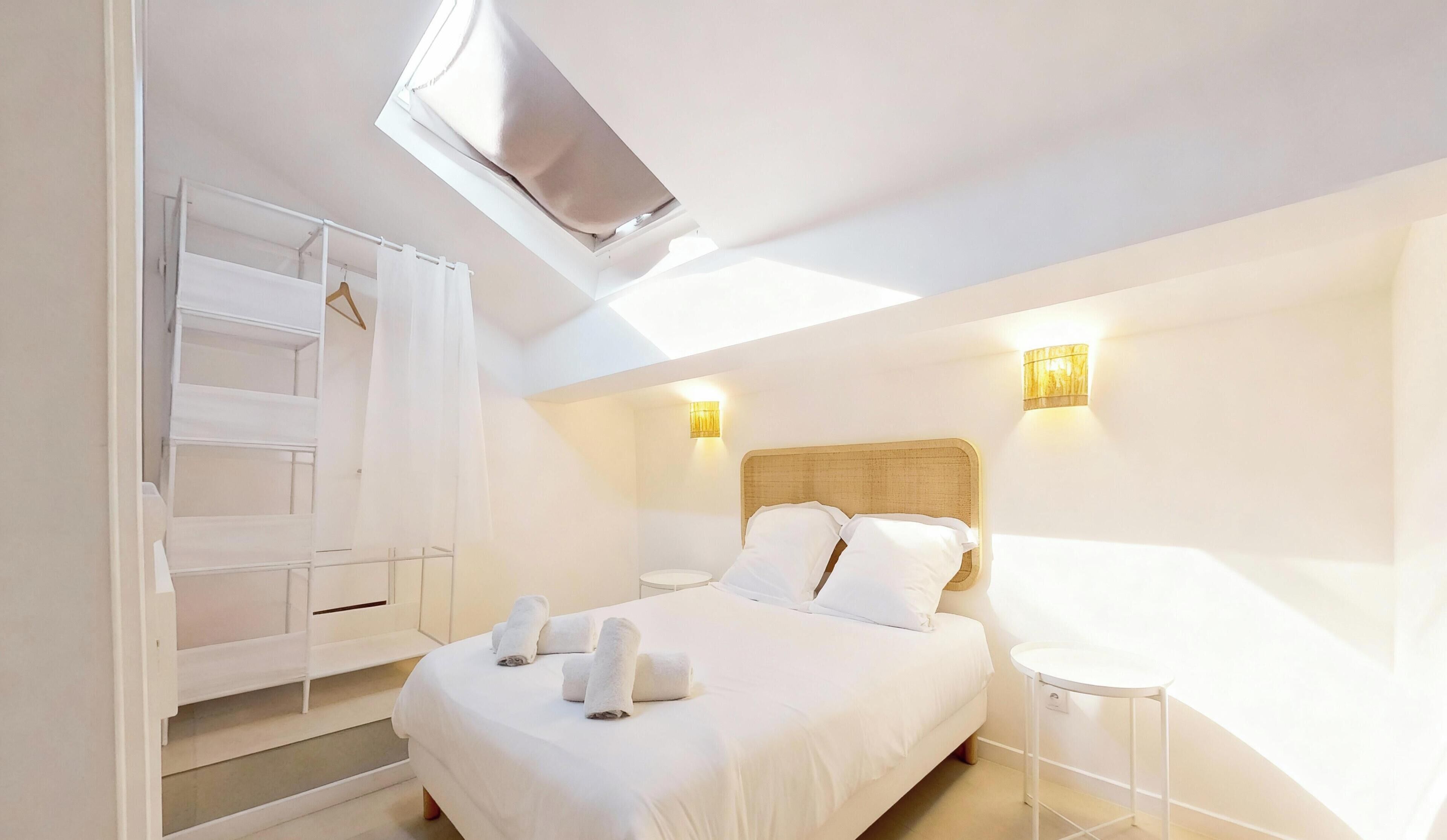 Una camera d'albergo con un letto, un armadio, un tavolino e una lampada a soffitto.